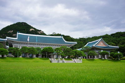 Built structure on field by houses against sky