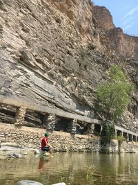 Rear view of woman walking on rock by water