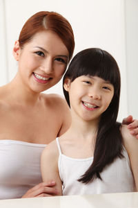 Portrait of smiling mother and daughter at home