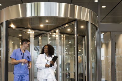 Smiling multiracial male and female doctors walking in front of revolving door