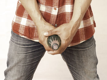 Midsection of man holding hands standing against wall