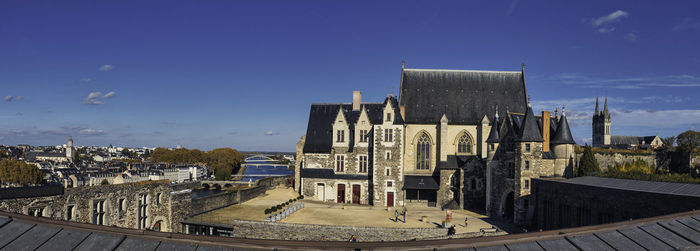 High angle view of buildings in city against blue sky