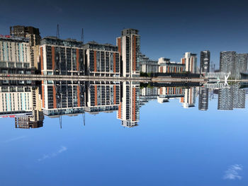 Reflection of buildings in lake against blue sky