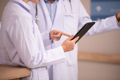 Midsection of doctor using mobile phone