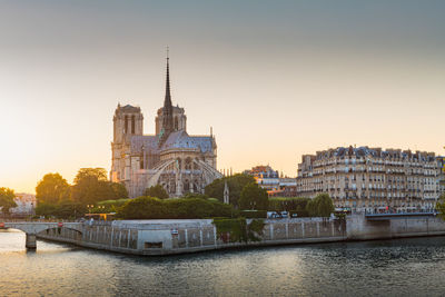 Buildings by river against sky