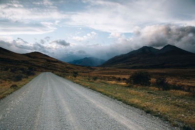 Road leading towards mountains against sky