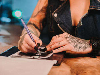 Midsection of woman holding hands on table