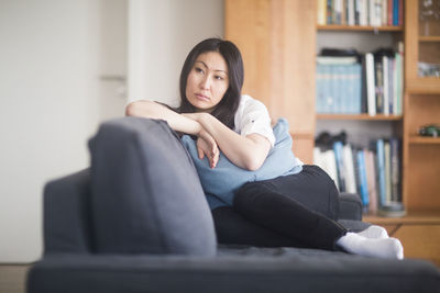 Young woman at home in a living room lying on a couch revised