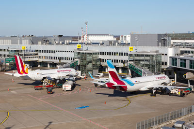 Airplane on airport runway against sky in city