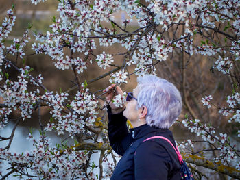 Side view of woman holding cherry tree branches 