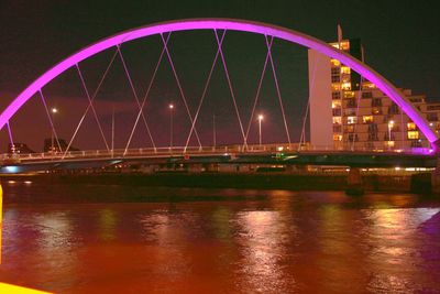 Illuminated suspension bridge over river at night