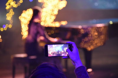 Cropped hand of woman filming with mobile phone in party