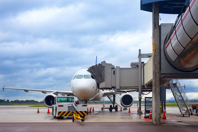 Airplane on airport runway against sky