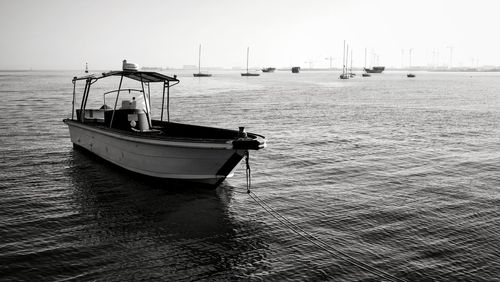 Sailboats moored on sea against clear sky