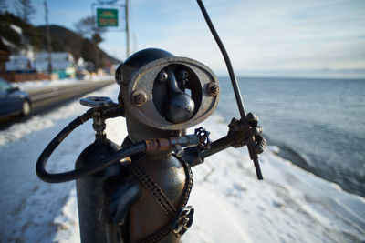 Close-up of coin-operated binoculars on sea against sky