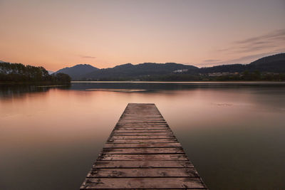 Pier over lake against sky during sunset