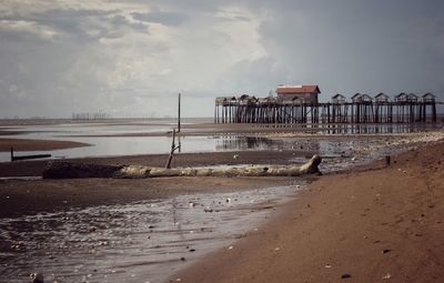 Pier on beach against sky