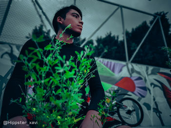 Young man looking away while sitting in yard