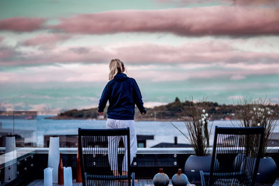 Rear view of woman standing on building terrace against sky