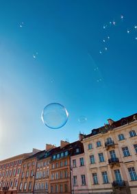 Low angle view of bubbles against building against sky