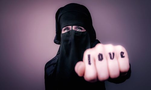 Portrait of woman wearing nikab with love tattoo on fingers