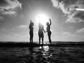 Silhouette people at beach against sky