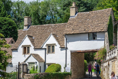 People outside house amidst trees and buildings in city