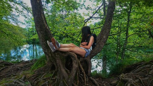 Woman sitting on tree trunk in forest