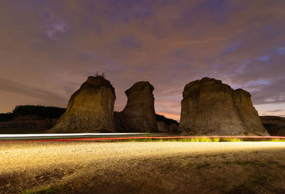 Scenic view of rocks on field against sky at sunset