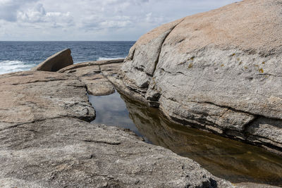 Rock formation on beach against sky