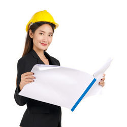 Portrait of smiling young woman standing against white background