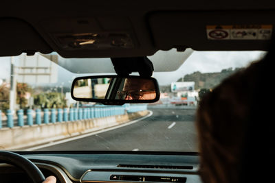 Man reflecting in rear-view mirror of car