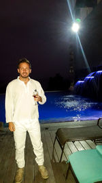 Portrait of a young man drinking water from swimming pool