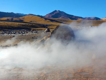 Smoke emitting from hot spring geyser against clear sky