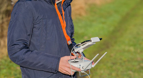 Midsection of man with drone on field