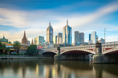 Bridge over river in city against sky