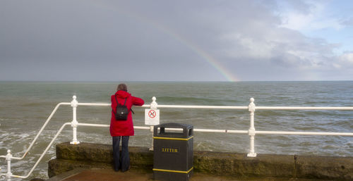 Rear view of rainbow over sea against sky