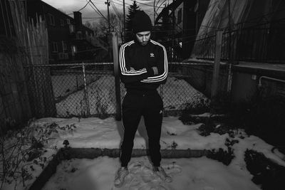Full length portrait of woman standing on snow covered street during winter