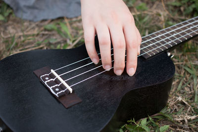 Cropped image of person playing guitar on field