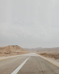 Empty road amidst mountains against sky