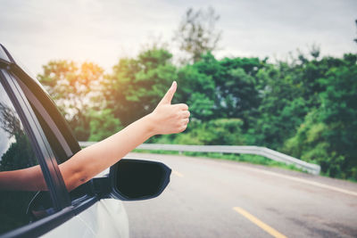 Cropped hand gesturing in car on road