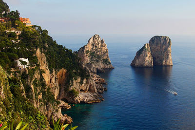 Rock formations in sea against blue sky