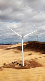 Windmills on landscape against sky