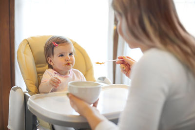 Portrait of mother and daughter sitting on table