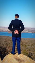 Rear view of army man with hands behind back standing on cliff