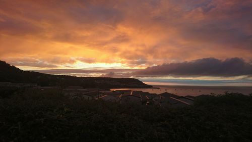 Scenic view of sea against dramatic sky during sunset