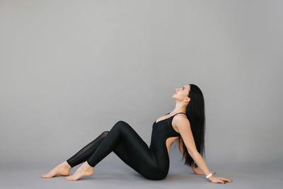 Rest between workouts. a pretty young woman with a good athletic form in a black jumpsuit is sitting