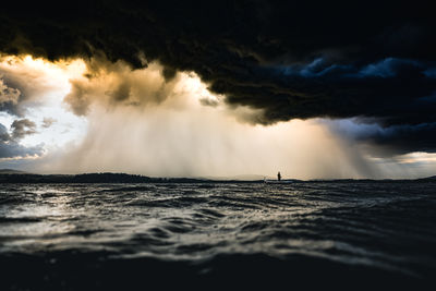 Fisherman on his boat on lake during approaching storm