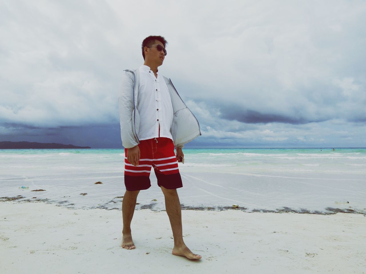 full length, cloud - sky, leisure activity, sky, standing, lifestyles, water, sea, beach, casual clothing, vacations, horizon over water, young adult, front view, scenics, person, tourism, shore, beauty in nature, tranquil scene, nature, travel destinations, tranquility, cloud, day