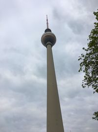 Low angle view of communications tower against cloudy sky